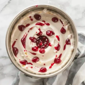 Swirling Raspberry Preserves into Bundt Cake Batter Top view of raspberry preserves being swirled into bundt cake batter inside a bundt pan
