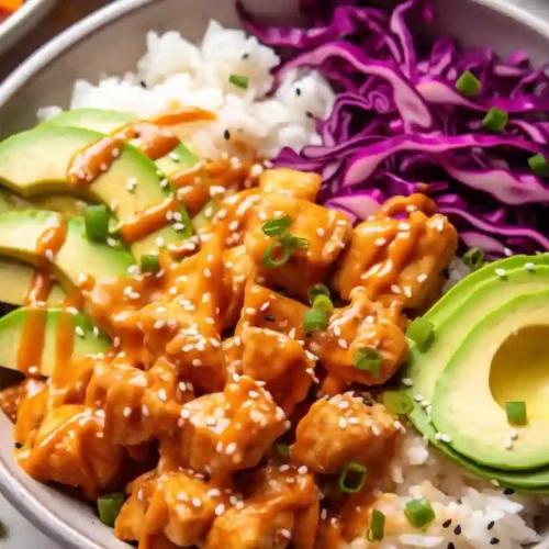 Bang Bang Chicken Bowl 4 Close-up of a Bang Bang Chicken Bowl with crispy chicken, avocado, shredded cabbage, cucumber, and creamy sauce