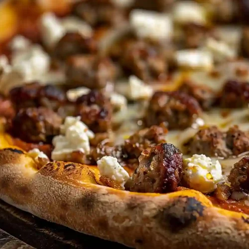 Close-up of a homemade hot sausage feta honey pizza with golden crust, melted mozzarella, and crumbled feta.