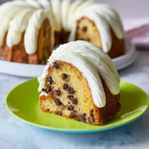 Single slice of Nothing Bundt Cake Classic Vanilla with chocolate chips and cream cheese frosting on a colorful plate