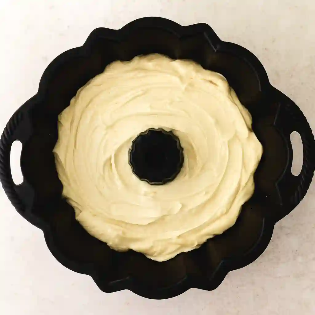 The Best Coconut Bundt Cake You’ll Ever Bake 6 Coconut Bundt Cake batter spread evenly in a greased bundt pan, ready to go into the oven