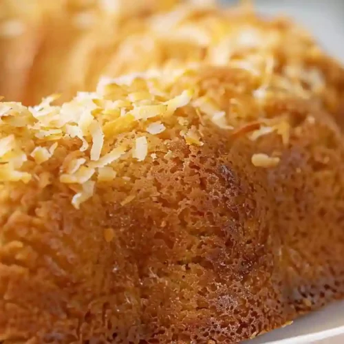 Moist golden coconut pineapple bundt cake topped with toasted shredded coconut