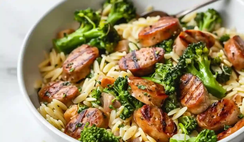 Bowl of chicken sausage and broccoli orzo in natural light