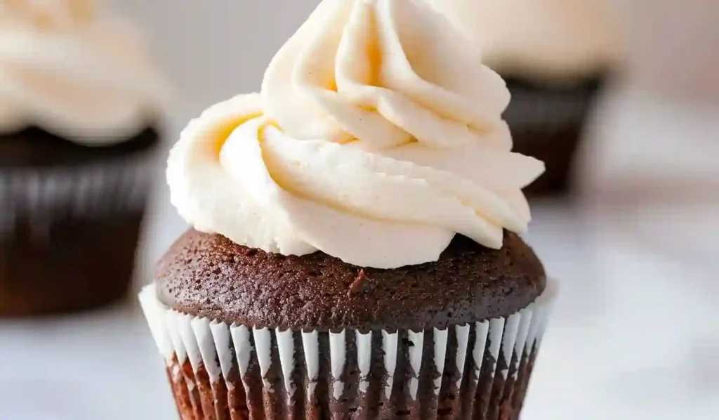 Close-up of a chocolate cupcake topped with smooth vanilla buttercream frosting.