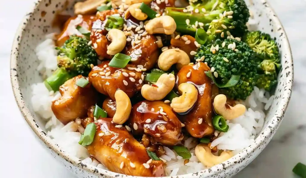 Close-up bowl of cashew chicken served over rice with broccoli, soft natural lighting