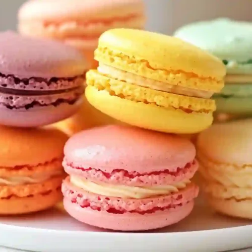 Extra close-up of assorted colorful French macarons stacked and arranged on a clean plate under soft natural light