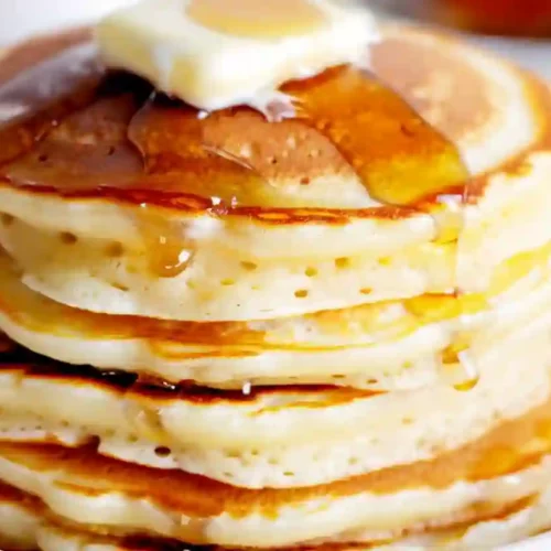 Stack of fluffy golden pancakes made from pancake mix with butter melting on top