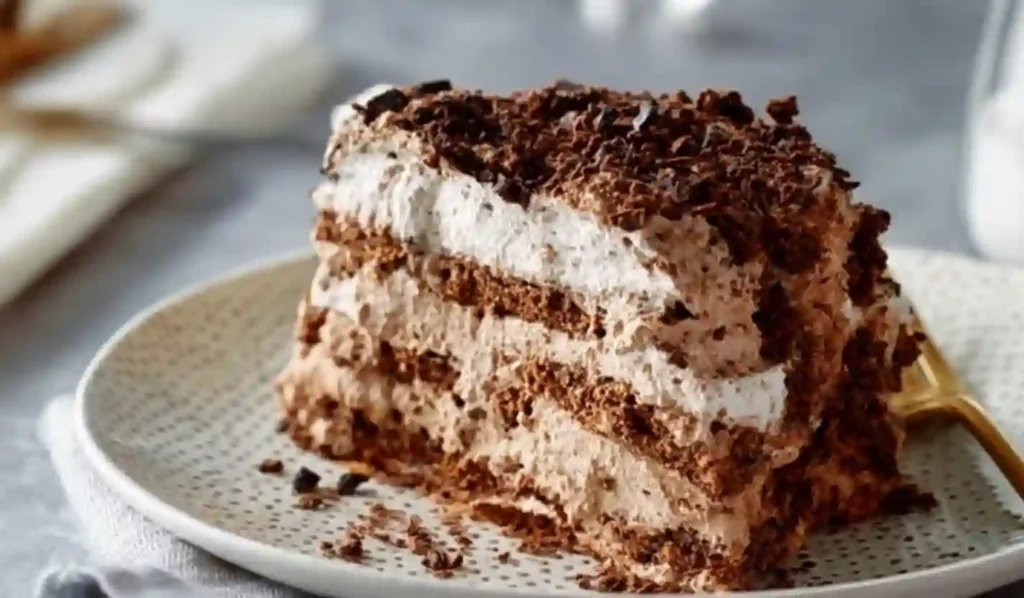 Extra close-up slice of chocolate icebox cake with whipped chocolate cream and cookie layers on a patterned plate