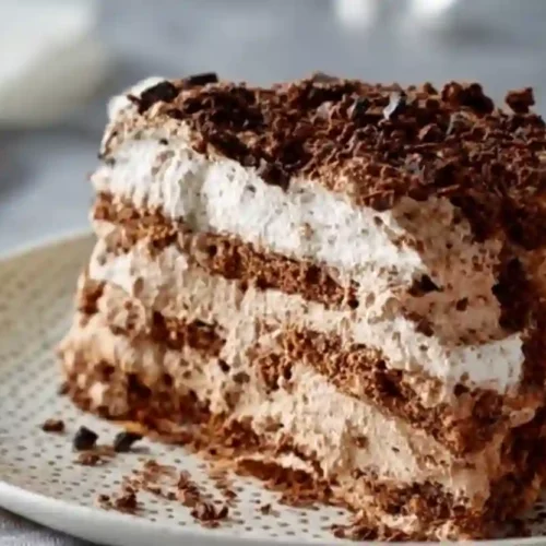 Extra close-up slice of chocolate icebox cake with whipped chocolate cream and cookie layers on a patterned plate