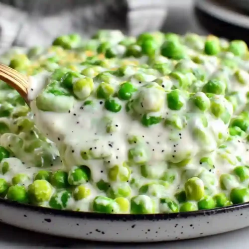 Extra close-up of creamy green peas coated in thick white sauce served warm
