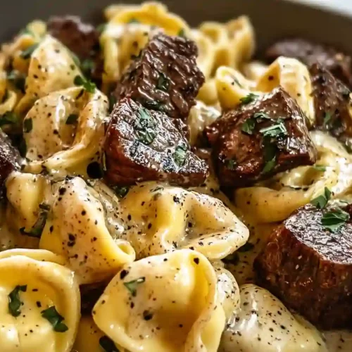 Extra close-up of garlic steak tortellini coated in creamy sauce with seared beef pieces