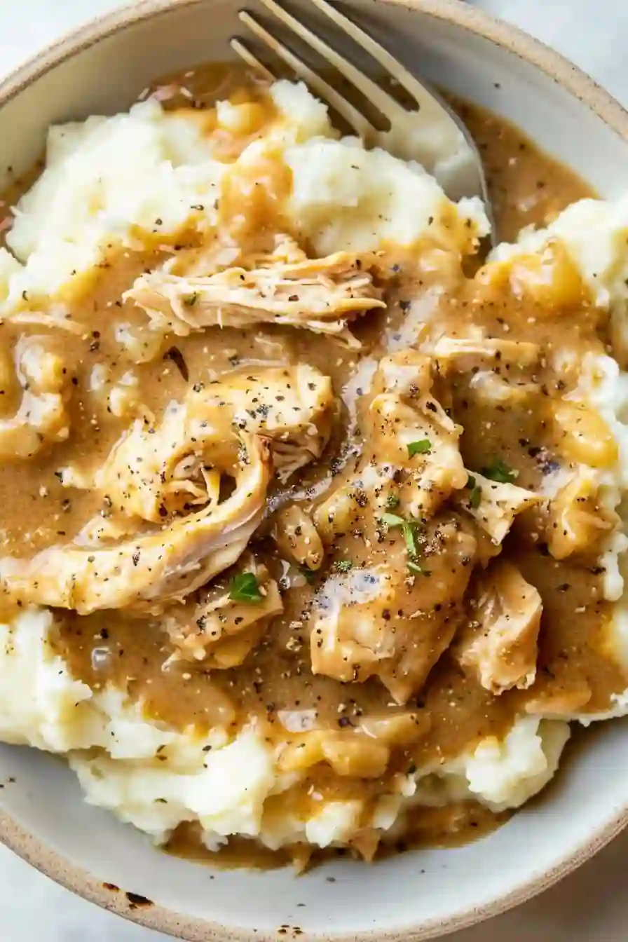 Vertical image of chicken and gravy over mashed potatoes with creamy texture
