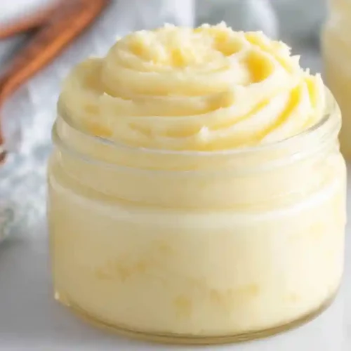 Creamy homemade honey butter swirled inside a small glass jar on a light surface