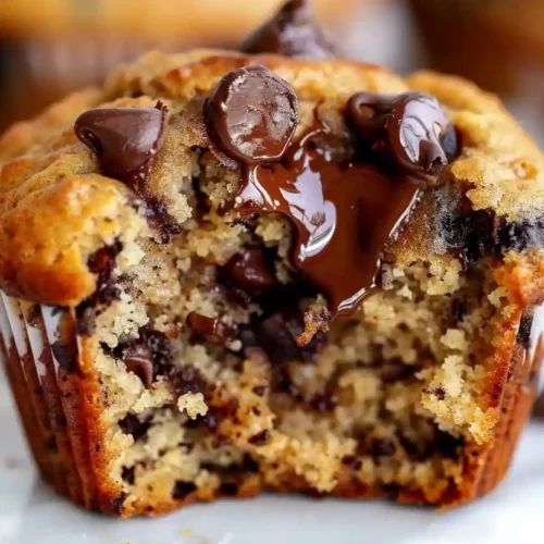 Close-up of a moist banana muffin with melted chocolate chips, broken open to show soft texture