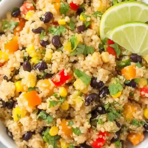 Southwest Quinoa Salad for Cozy, Protein-Packed Weeknights 3 Close-up of southwest quinoa salad with black beans, corn, red bell peppers, cilantro, and lime wedges in a bowl