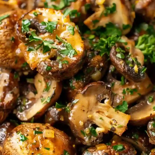 Extra close-up of golden brown air fryer mushrooms garnished with chopped parsley in a white bowl