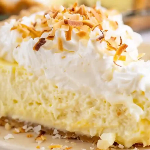 Extra close-up slice of coconut cream pie with whipped cream and toasted coconut flakes
