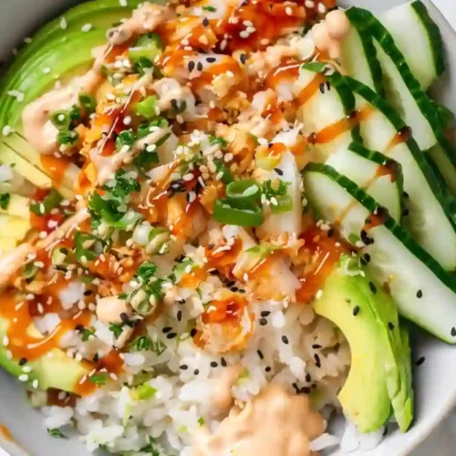 Close-up crunch roll sushi bowl with avocado, cucumber, crab mix, rice, spicy mayo and teriyaki drizzle on marble countertop
