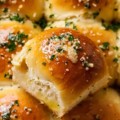Extra close-up of golden garlic butter bread rolls with parsley flakes in a baking dish