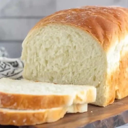 Homemade white sandwich bread loaf sliced on a wooden board with soft interior crumb