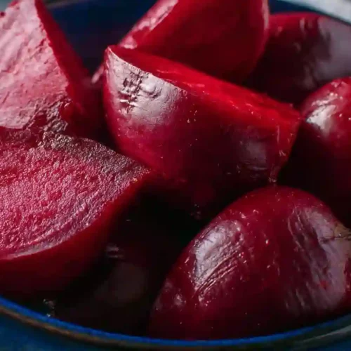 Close-up of glossy red Instant Pot beets in a dark blue bowl