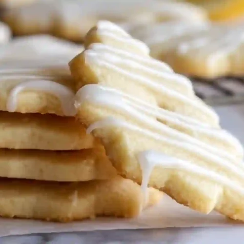 Close-up lemon shortbread cookies topped with smooth lemon glaze on parchment paper
