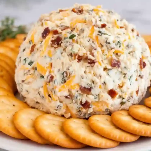 Cheddar ranch cheeseball served with round golden crackers on a white plate