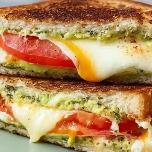 Extra close-up tomato mozzarella grilled sandwich with avocado spread and melted cheese on toasted bread