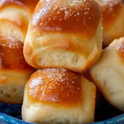 Golden brown cloverleaf dinner rolls stacked in a blue bowl