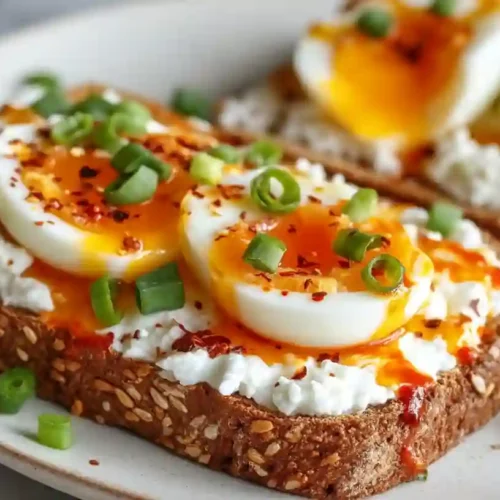 Toast with cottage cheese and soft-boiled eggs topped with chili flakes and green onions