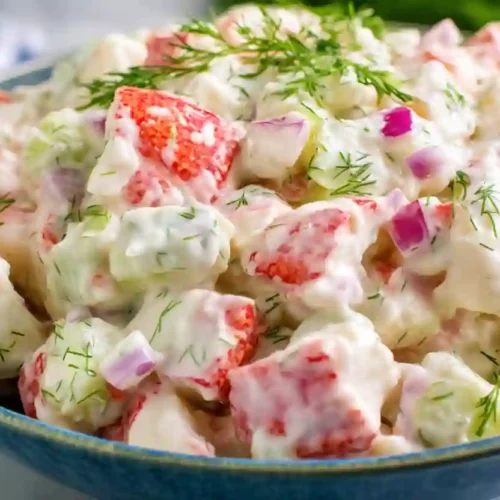 Close-up creamy crab salad with dill, celery, and red onion in a bowl