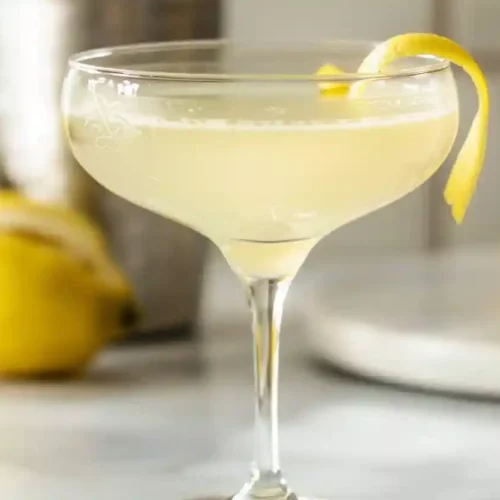 French 75 mocktail served in a coupe glass with lemon twist garnish on marble countertop