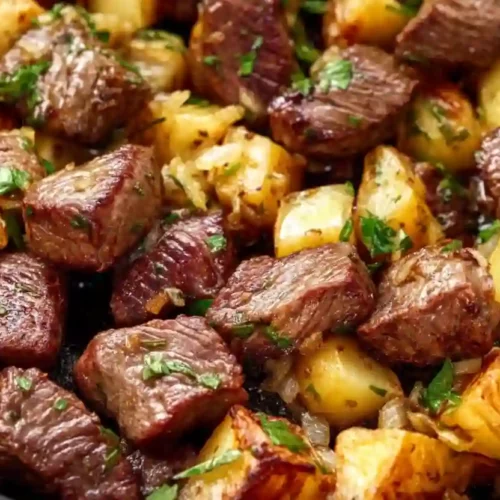 Close-up skillet of garlic butter steak bites with crispy golden potatoes