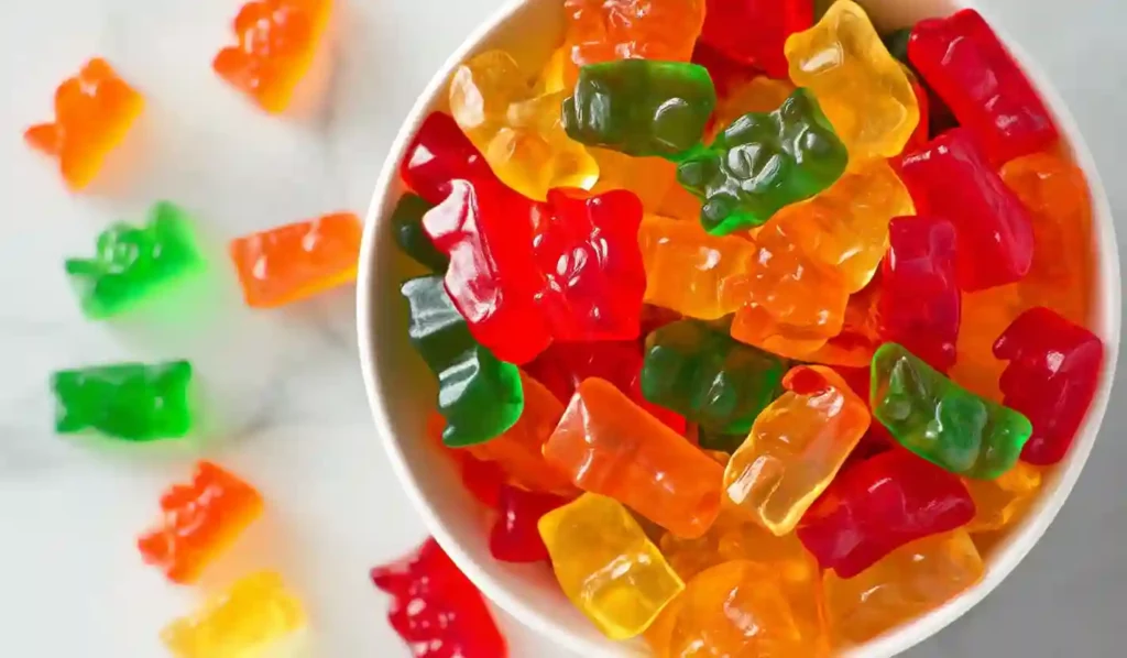 Colorful gummy bears in a bowl close-up on white marble countertop