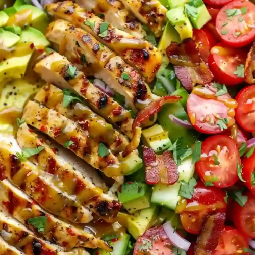 Honey mustard chicken salad with avocado, cherry tomatoes and bacon in a wooden bowl