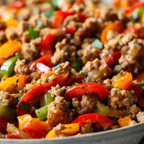 Ground turkey cooked with colorful bell peppers and onions in a skillet
