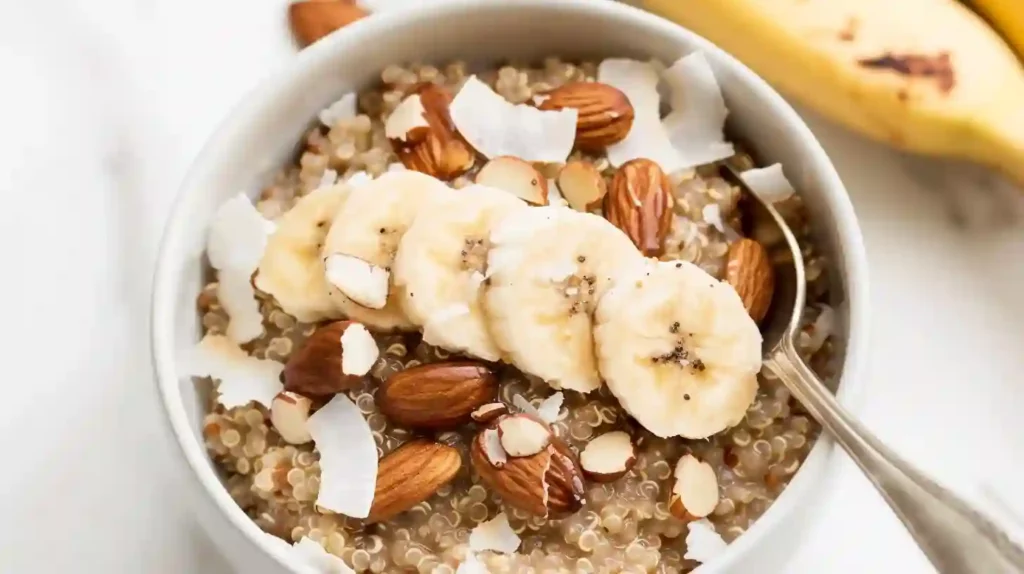 Close-up quinoa breakfast bowl with banana slices, almonds, and coconut flakes