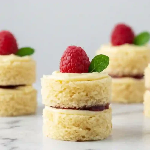Mini Victoria sponge cakes filled with jam and topped with raspberries and cream