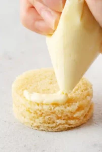 piping Vanilla Buttercream onto Mini Cakes